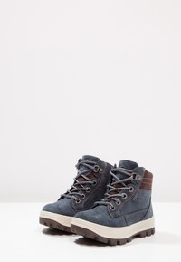 Blaue Wildlederstiefel mit braunen Akzenten, ausgestattet mit Metallösen, Schnürsenkeln und einer dicken, strukturierten Gummisohle für besseren Halt.
