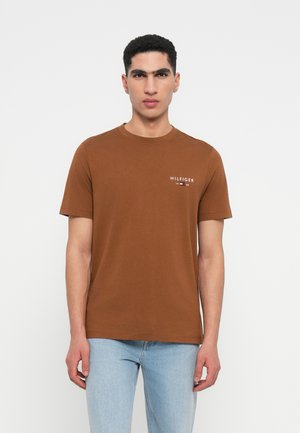 Barna pamut póló rövid ujjal és kerek nyakkivágással. Bal mellrészen egy kis fehér logó található. Szabványos szabás, sima textúra.