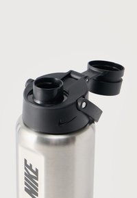 Ασημένιο παγούρι της Nike με μαύρο καπάκι τύπου flip-top ανοιχτό, που δείχνει ευρύ στόμιο και ασφαλές κλείστρο σε απλό λευκό φόντο.