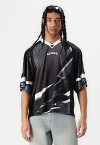 Maillot à manches courtes noir et gris avec un motif diagonal, texture en maille, accents blancs et logo Adidas sur la poitrine.