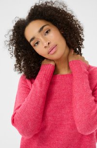 Pull rose vif fabriqué à partir d'un matériau doux, doté d'un col rond classique et de poignets côtelés. La texture semble confortable et chaude.