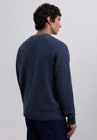 Suéter de lana azul marino con un acabado texturizado, cuello redondo y puños y dobladillo de punto acanalado. Corte casual con detalles moteados por todo el suéter.
