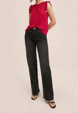 Top rosso senza maniche con dettagli in volant, abbinato a jeans neri a vita alta e gamba larga e sandali neri. Outfit semplice e casual.
