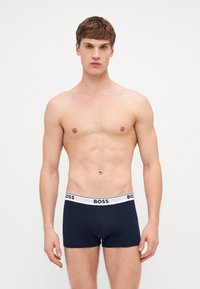 Navy-Boxershorts mit einem weißen elastischen Bund, auf dem das "BOSS"-Logo prangt. Der Stoff ist glatt und körperbetont, was ein schlankes Design hervorhebt.