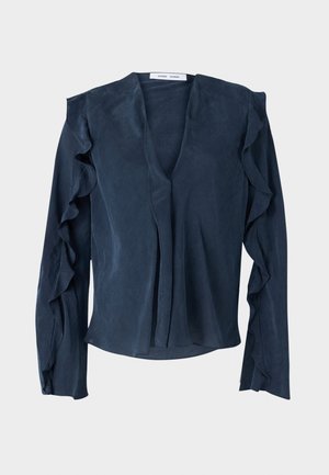 Tums zila blūze no viegla auduma ar dziļu V veida kakla izgriezumu, garām piedurknēm ar volāniem un brīvu piegriezumu apakšmalā.