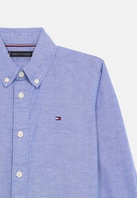 Lys blå skjorte med knapp-down krage og liten Tommy Hilfiger-logo brodert på brystlommen.