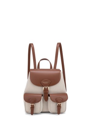 Sac à dos en tissu beige avec rabat en cuir marron, deux poches avant, bretelles réglables et boucles dorées.