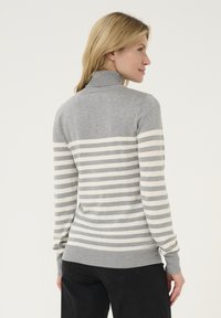 Siv turtleneck pulover z diagonalnimi sivimi in kremnimi črtami, rebrastim zaključkom rokavov in roba ter mehkobo pletenine.