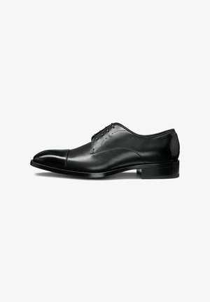 Black leather dress shoe with a rounded toe, smooth finish, five eyelets, and a low, stacked heel. Features subtle stitching details.