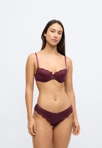 Vīnogu sarkanas krūštura ar mežģīnēm un regulējamām lencītēm, atbilstoši biksītēm ar mežģīņu akcentu un mazu loku priekšpusē, gluda materiāla.