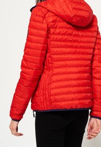 Czerwona pikowana kurtka z kapturem, z poziomymi panelami, elastycznymi mankietami oraz granatowym obszyciem na dole. Materiał wygląda na połyskliwy i lekki.