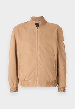 Tan bomber jacket featuring a ribbed collar, front zipper, two side pockets, and elastic cuffs with a small zip pocket on the left arm.
