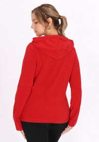 Hanorac roșu din fleece cu glugă ajustabilă, mâneci lungi și o textură moale. Designul prezintă o siluetă simplificată și o cădere naturală.