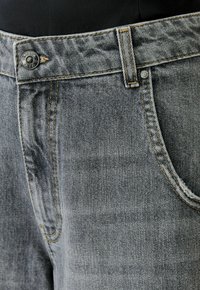 Graue Denim-Jeans mit klassischem Fünf-Taschen-Design, kupferfarbenen Nähten und einer Metallknopfverschluss am Bund.