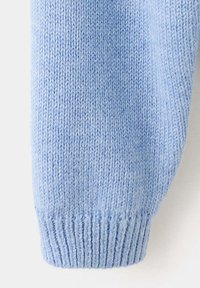 Manche de pull tricoté bleu clair avec bord-côte sur fond blanc, montrant une texture de tricot détaillée.