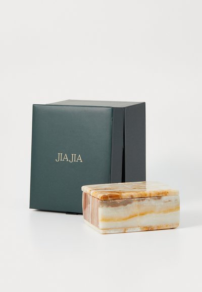 Rektangulär låda i onyx med en slät yta, i nyanser av grädde, orange och brunt, bredvid en mörkgrön presentlåda märkt "JIA JIA."