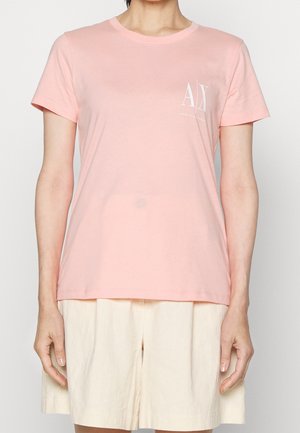 Lyserød bomulds-T-shirt med korte ærmer og rund halsudskæring, med en hvid logo på venstre brystområde.