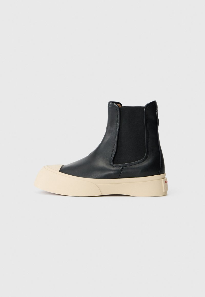 Stivaletti neri in pelle con punta rotonda e suola piatta beige. Caratterizzati da lati elasticizzati per una facile calzata e una texture liscia.