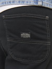 Zwarte katoenen denim broek met een zichtbare achterzak met een rechthoekig merketiket. Contrasterende stiksels en een gladde textuur.