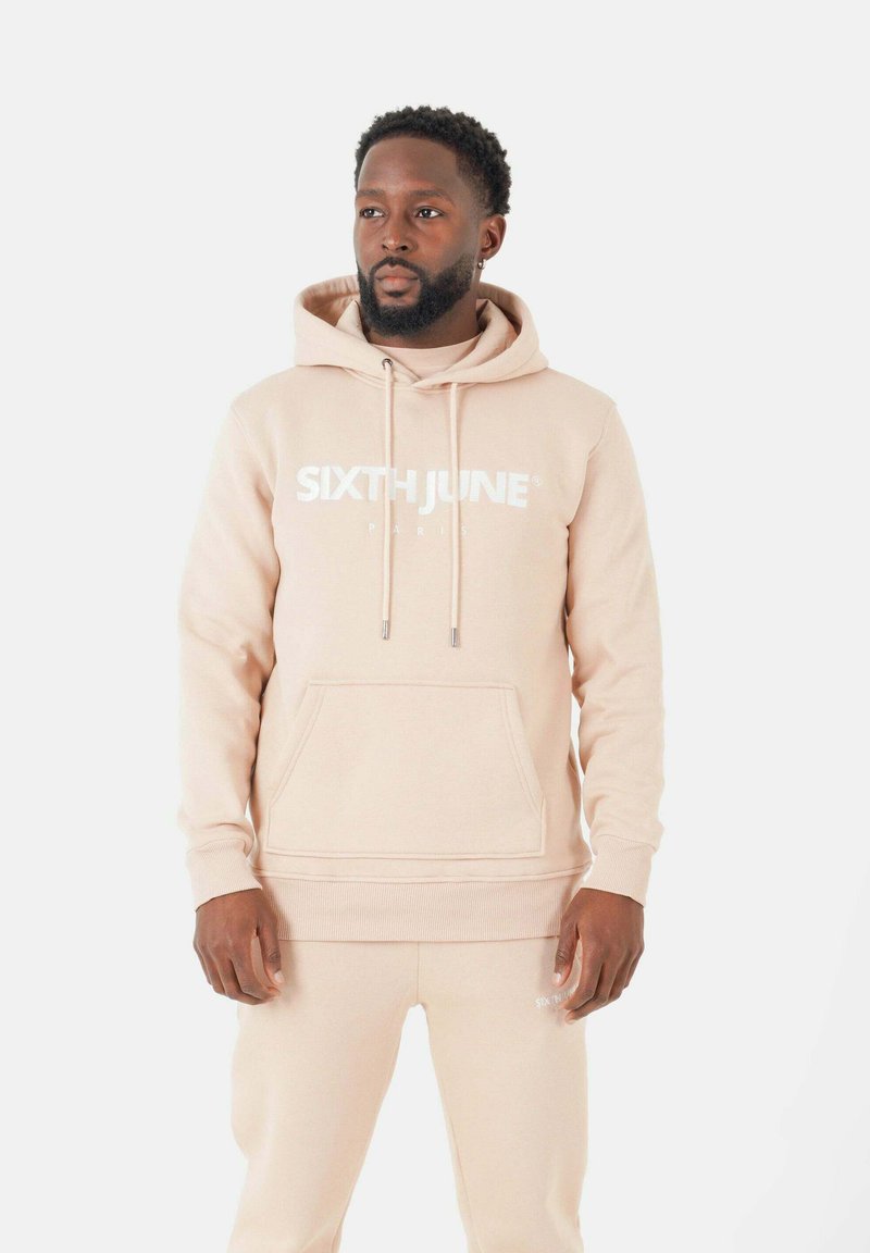 Hoodie beige avec une poche kangourou à l'avant, des cordons de serrage et un logo "SIXTH JUNE" en relief blanc. À assortir avec un pantalon beige assorti.