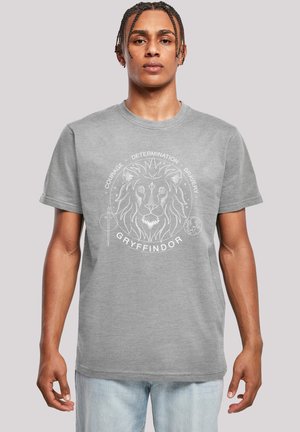 Grå t-skjorte med korte ermer som har et hvitt løvegrafikk med teksten "GRYFFINDOR" og ordene "KRAFT," "BESTEMMELSE," og "DRAKTFULLHET."