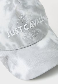 Cappello grigio con un logo "JUST CAVALLI" bianco lucido, caratterizzato da un tessuto testurizzato e una visiera arrotondata. Sottile motivo marmorizzato sulla superficie.