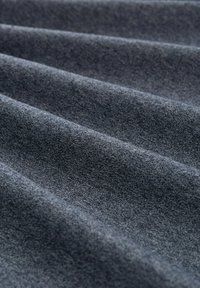 Donkergrijze stof met een zachte textuur, voorzien van geplooide vouwen die een golvend patroon creëren. Het materiaal lijkt duurzaam en stevig geweven te zijn.