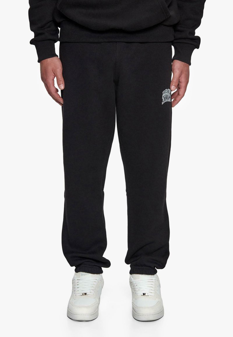 Sorte sweatpants lavet af blødt stof, udstyret med en elastisk talje og manchetter, med et hvidt logo-patch på venstre lår.