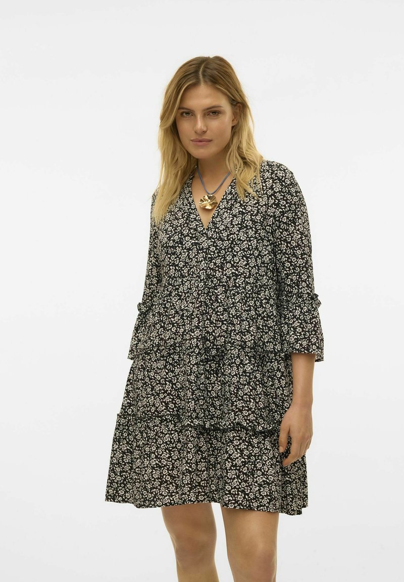 Vestido negro con estampado floral que presenta un diseño en capas, mangas tres cuartos, escote en V y una tela ligera con patrones florales blancos.