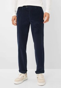 Pantaloni in corduroy blu navy con design a gamba dritta, caratterizzati da chiusura con bottone e tasche frontali, abbinati a sneakers beige chiaro.