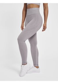 Grå højtaljede leggings med teksturerede m�ønsterdetaljer, strækbart stof og tætsiddende pasform, parret med hvide atletiksko.