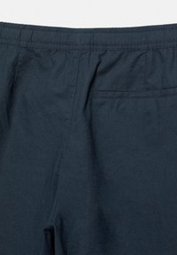 Dunkel marineblaue Hose mit elastischem Bund und einer einzelnen horizontalen Gesäßtasche auf der rechten Seite.