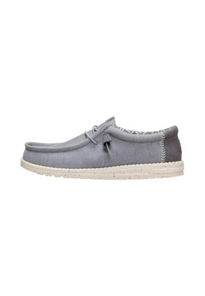 Scarpa casual grigia slip-on con suola bianca maculata, tomaia morbida, dettaglio di lacci sul lato e colletto imbottito sul tallone che mostra l'interno decorato.