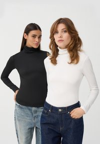 Dwa golfy: jeden czarny, a drugi biały. Oba są dopasowane, z długim rękawem, wykonane z gładkiego materiału i mają wysokie kołnierze.