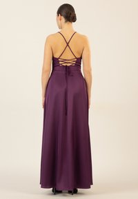 Langes lila Satin-Kleid mit einem figurbetonten Oberteil, gekreuzten Rückenträgern und einem fließenden Rock. Verfügt über eine gebundene Akzentdetails am unteren Rücken.