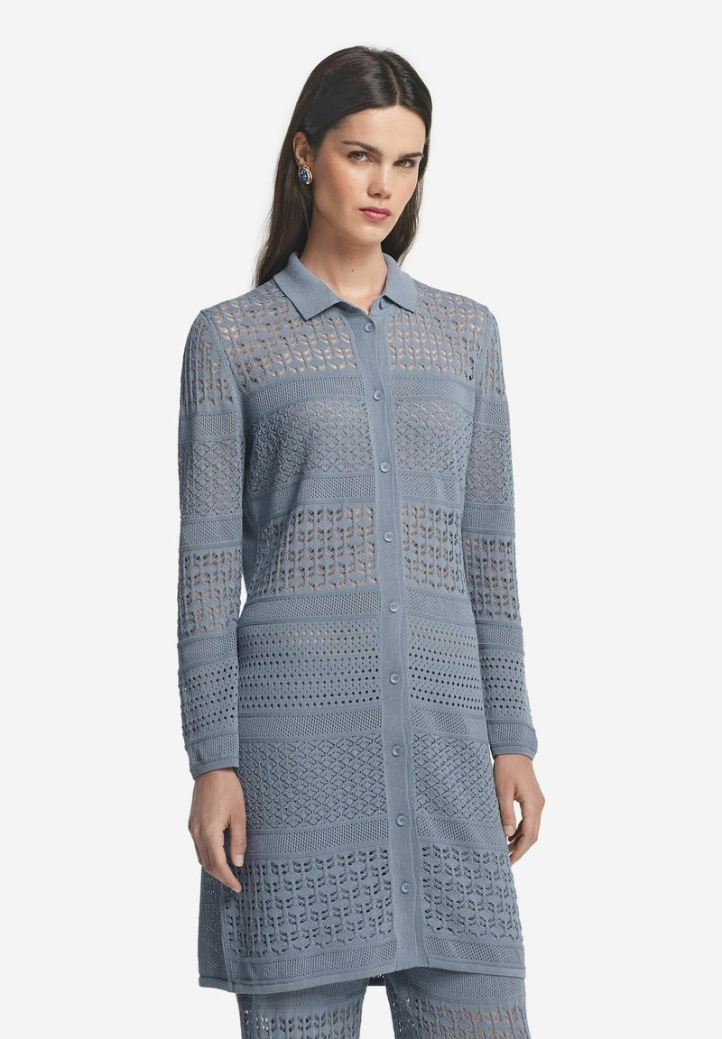 Ljusblå lång cardigan med knappstängning på framsidan, med intrikata öppna stickmönster och krage. Mjuk textur, slim fit.