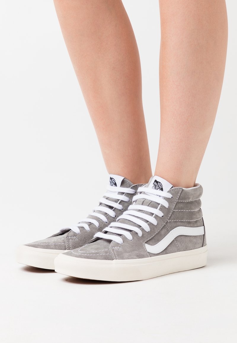 Wysokie sneakersy wykonane z szarego zamszu z białymi akcentami, posiadające sześć przelotek, płaskie białe sznurówki oraz teksturowany kołnierz.