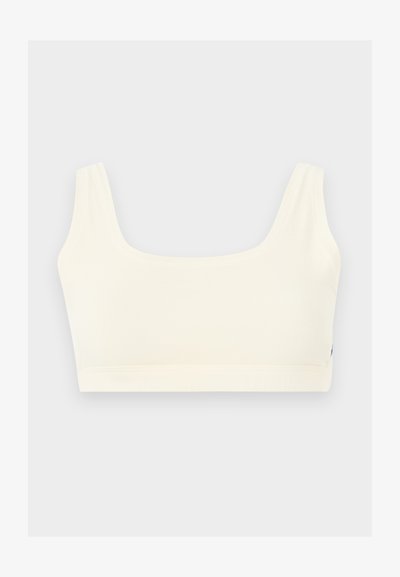 Λευκό αθλητικό σουτιέν χωρίς ραφές με φαρδιές τιράντες και τετράγωνο ντεκολτέ, εμφανίζεται σε ανοιχτό γκρι φόντο.