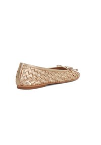Ballerines tressées en or avec un profil bas, une texture douce et un accent de nœud délicat sur le bout. Semelle plate avec un léger bord marron.