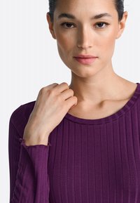 Purple ribbed long-sleeve top with a rounded neckline and textured detail. Sleeves feature subtle frayed edges, creating a relaxed look.