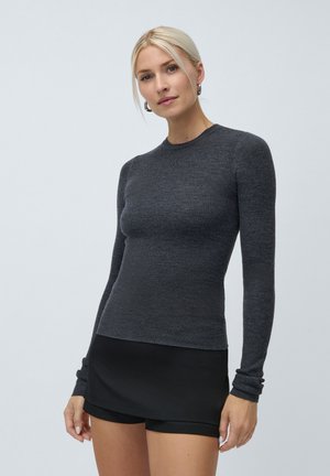 Ribbet langermet topp i mørkegrå, med rund hals og tettsittende silhuett. Kombinert med sorte shorts.