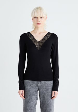 Black long-sleeve shirt with a V-neck design featuring a lace accent. Soft material with a fitted silhouette, paired with gray jeans.