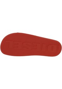 Semelle intérieure de chaussure rouge avec une surface lisse, présentant un motif texturé pour l'adhérence, et un logo en relief au centre.