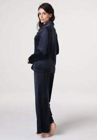 Set di pigiama in velluto blu navy con top con colletto e pantaloni lunghi. Texture morbida con una vestibilità rilassata. Dettagli di cucitura a contrasto notevoli.