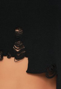 Fekete kötött anyag, kopott részletekkel, egyenetlen széllel és foszlott részekkel. Simaságú, közepes vastagságú és réteges megjelenésű.