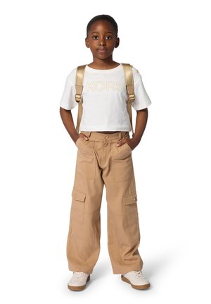 White cropped t-shirt with "KORS" in gold lettering, beige cargo pants with side pockets, gold backpack straps, and white sneakers.