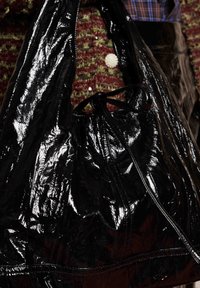 Μαύρο γυαλιστερό σακίδιο με κορδόνι, με υφή τσακισμένου υφάσματος, διαθέτοντας ραμμένη βάση και ασφαλές κλείσιμο. Περιλαμβάνει λεπτομέρειες από γυαλιστερό ύφασμα.