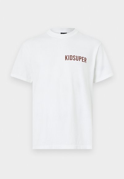 Λευκό βαμβακερό t-shirt με στρογγυλό λαιμό και κοντά μανίκια, με την επιγραφή "KIDSUPER" σε καφέ χρώμα στην αριστερή πλευρά.