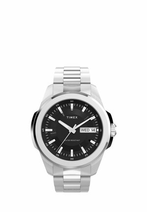 Stříbrné kovové hodinky Timex s černým ciferníkem, bílými hodinovými značkami a zobrazením dne a data, ukazující středu 14.