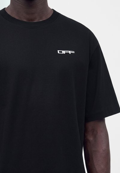 Μαύρο T-shirt που φοράει άτομο με σκούρο δέρμα, με μικρό λευκό κείμενο "OFF" στο πάνω αριστερό στήθος.